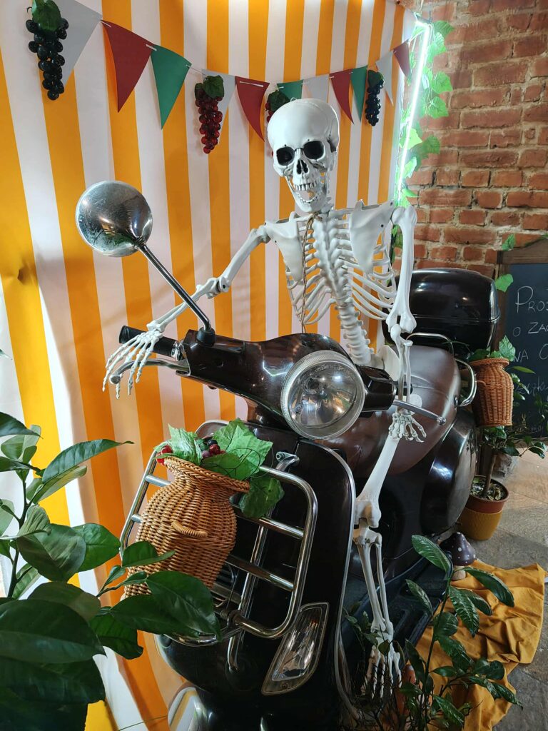 Dekoracja wnętrza restauracji włoskiej Toruń — szkielet na skuterze w klimacie włoskiej trattorii