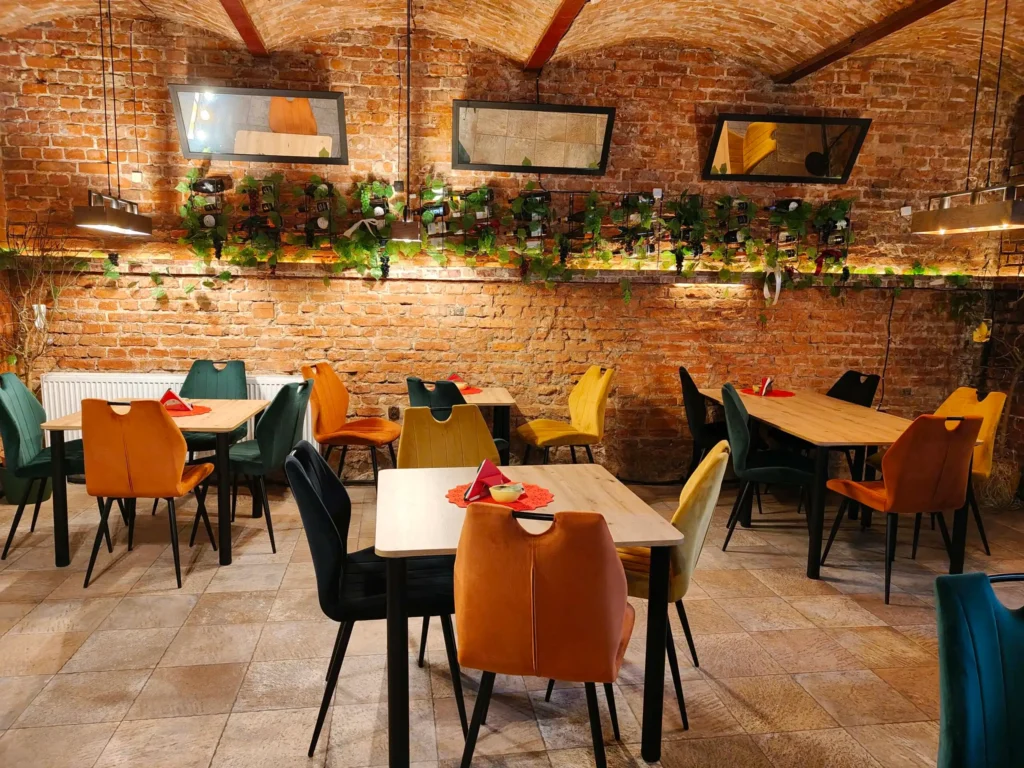 Stylowa sala z ceglanymi ścianami i kolorowymi fotelami w Restauracja O Sole Mio Italiano w Toruniu.